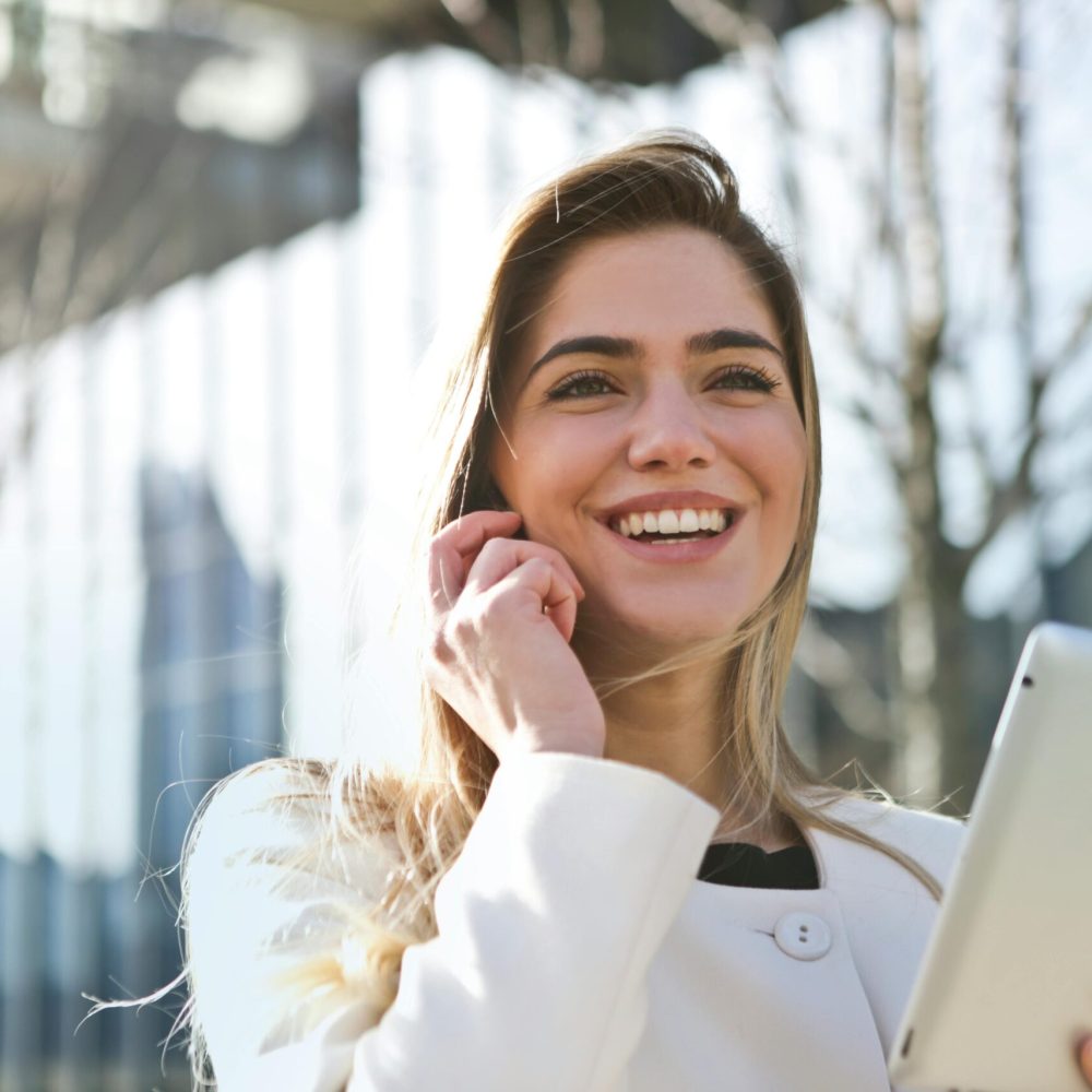 pexels-photo-789822-789822 Confident businesswoman using her tablet and phone, smiling outdoors in sunlight.